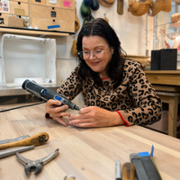 Woman using a rotary tool at a workbench with tools around