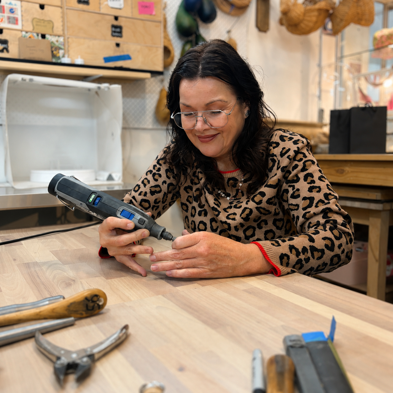 Woman using a rotary tool at a workbench with tools around