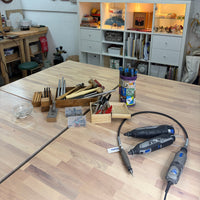 Tools and materials on a wooden table with a workshop background