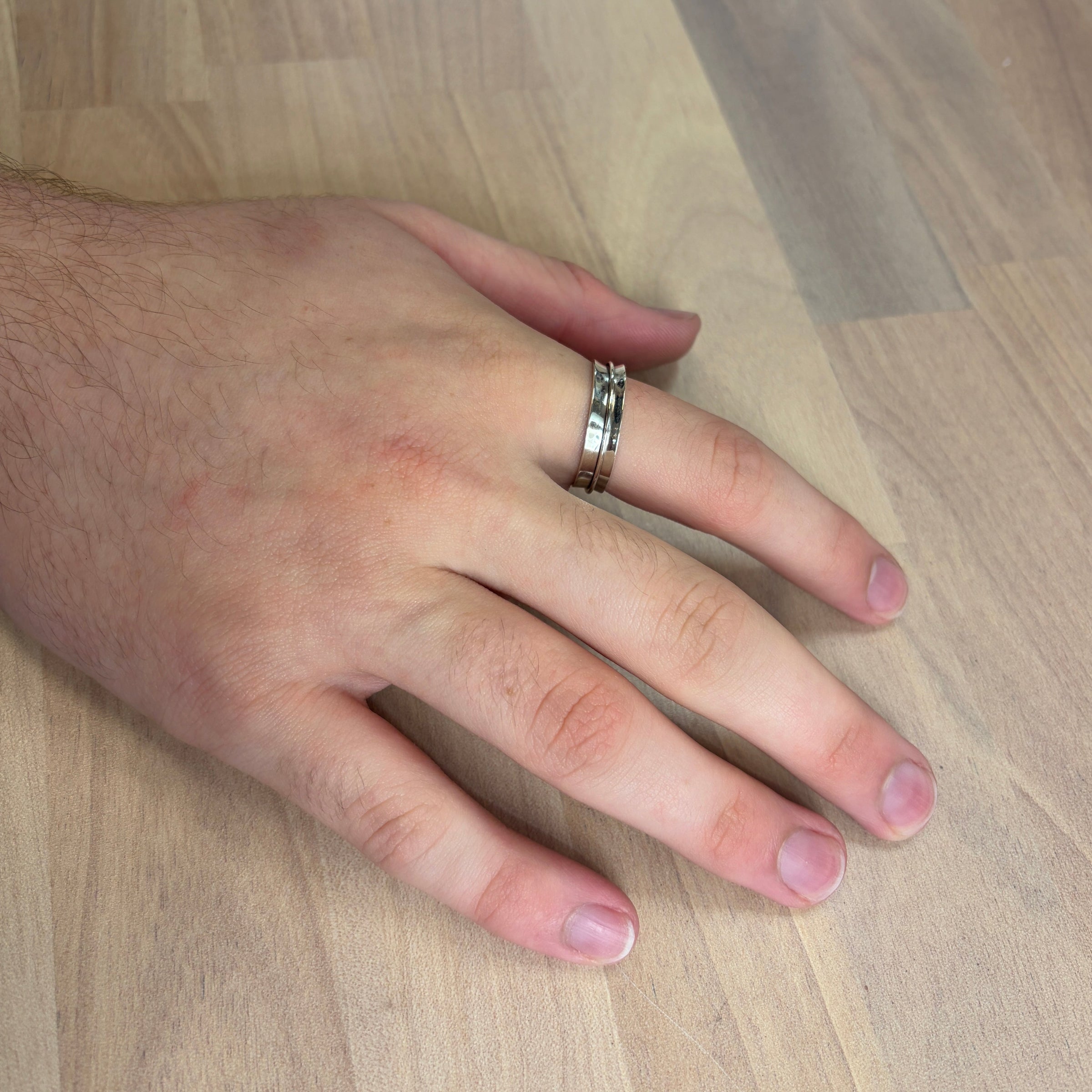 Hand with a ring on a wooden surface